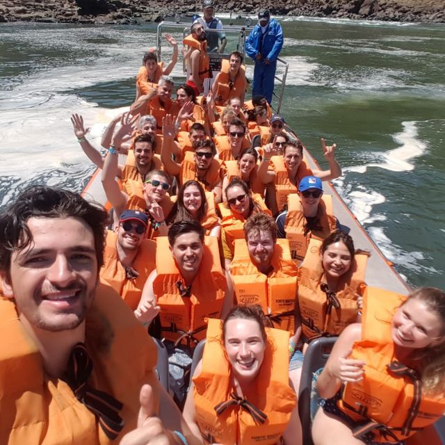 Eine Gruppe junger Menschen in dicken Schwimmwesten in einem Boot an der Wasserfällen von Iguazu.