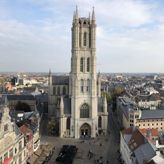 Der Blick geht von oben auf die gegenüber stehende Kathedrale. Die Kathedrale hat einen großen Turm aus hellen Stein. Rings herum befinden sich Gebäude.