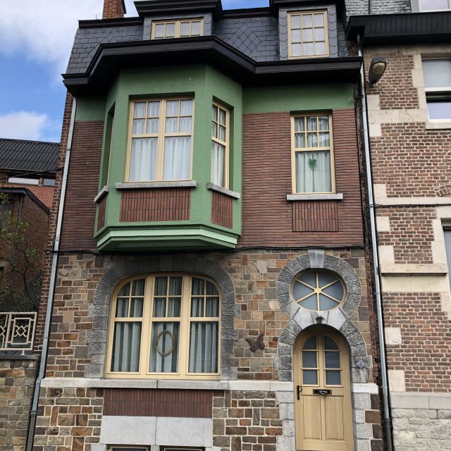 Ein Steinhaus mit grünen Fensterrahmen.