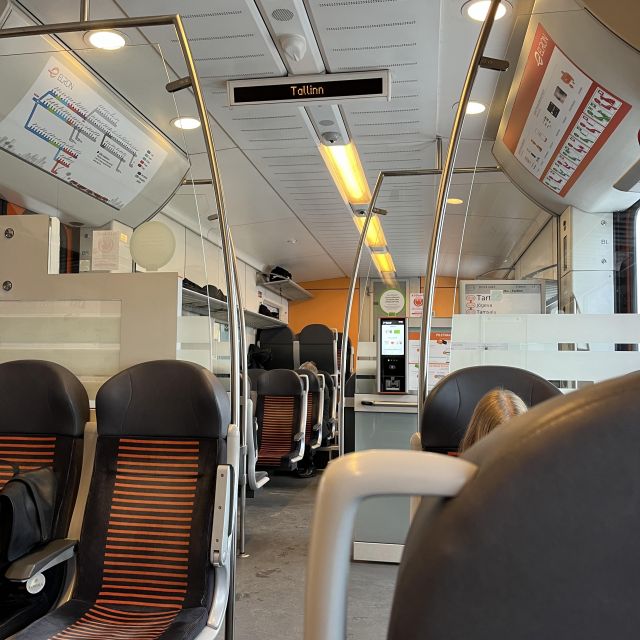 Zug von innen, geräumiger Wagon mit Stoffsitzen, die Anzeige zeigt Tallinn als Fahrtziel an.