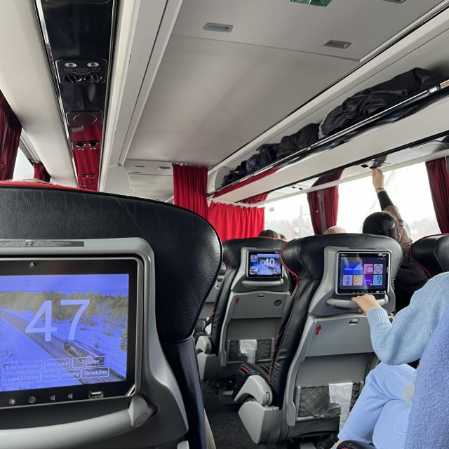 Reisebus von innen, mit Vorhängen an den Fenstern und Bildschirmen an jedem Sitz