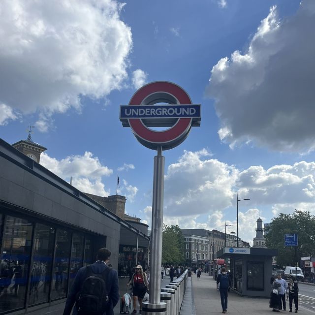 Blick auf eine Straße in London. Im Vordergrund sieht man ein Straßenschild mit einem roten Kreis. In dem Kreis steht auf blauem Hintergrund in weißer Schrift "Underground".