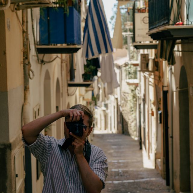 Man sieht mich wie ich fotografiere in einer kleinen gasse in Palermo mit vielen Balkons.