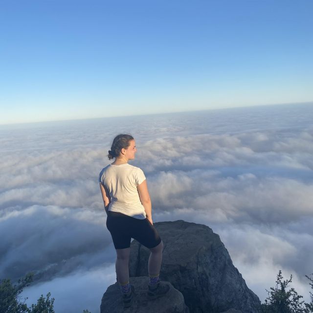 Frau am Gipfel des Lions Head unter ihr ein Wolkenmeer