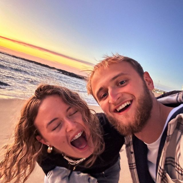 Eine junge Frau und ein Mann am Strand, die lachen, Selfie