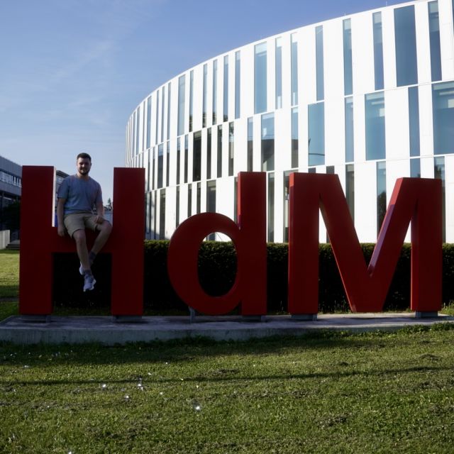 Mann sitzt auf HdM Buchstaben