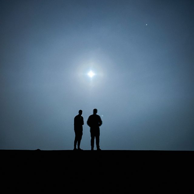 Zwei Personen, die auf eine Mauer bei Nacht stehen.