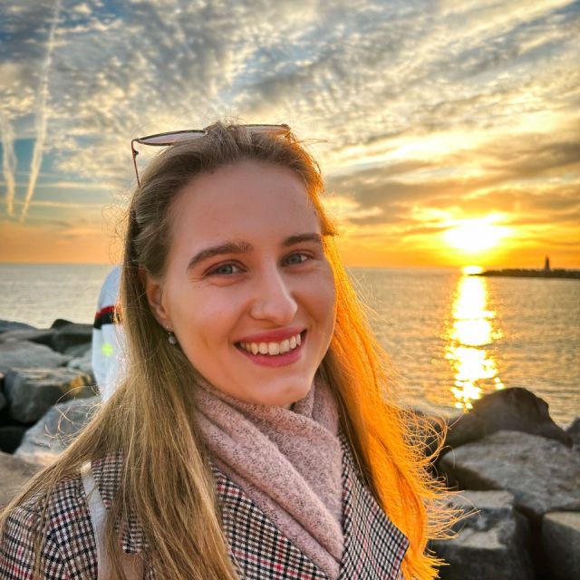 Eine hübsche junge Frau vor einem Sonnenuntergang am Meer.