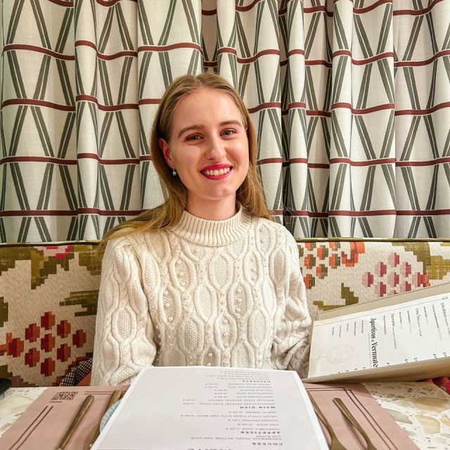 Eine junge Frau in einem Restaurant, sie hält das Menü in ihrer Hand.