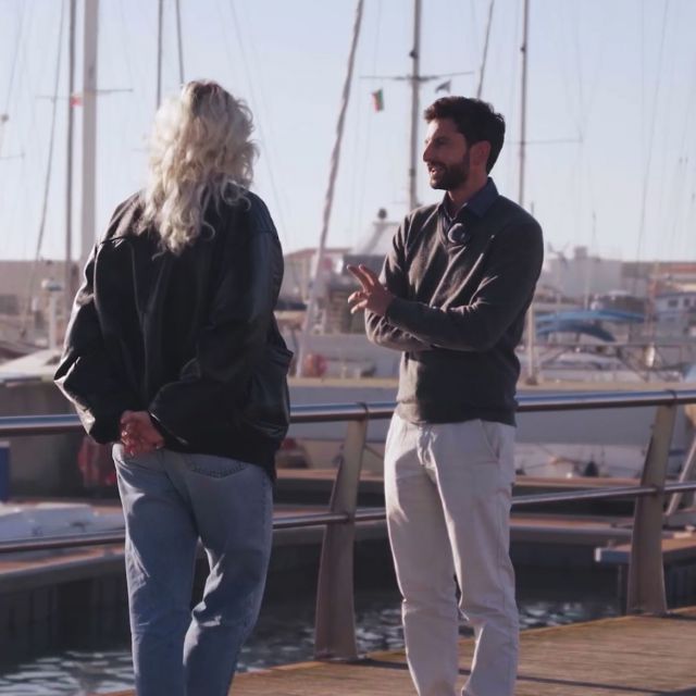 Zwei Personen im Gespräch, im Hintergrund ein Hafen