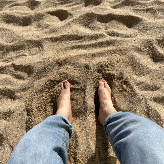 Zwei Füße, die im Sand versenkt sind.